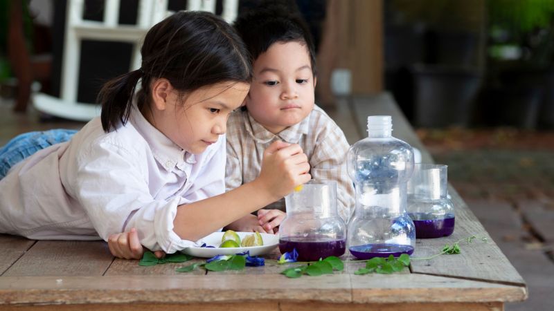 two children experiment with liquids in beakers