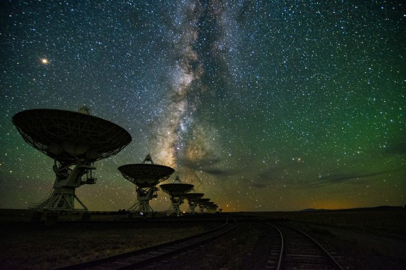 The Milky way galaxy is visible over radio telescopes at night