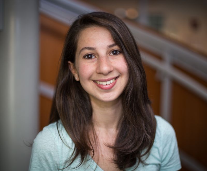 Katie Bouman smiles at the camera in front of an unfocused background