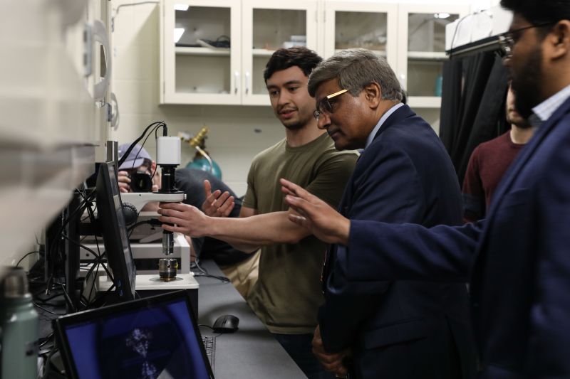 dr  Panchanathan stands in front of a scientific instrument with a student