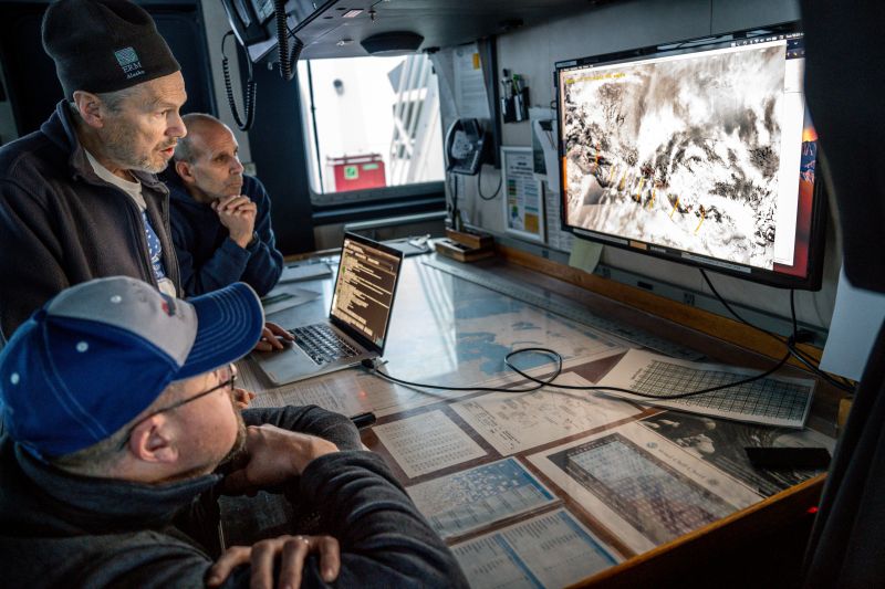 three polar scientists studying an image on a computer screen