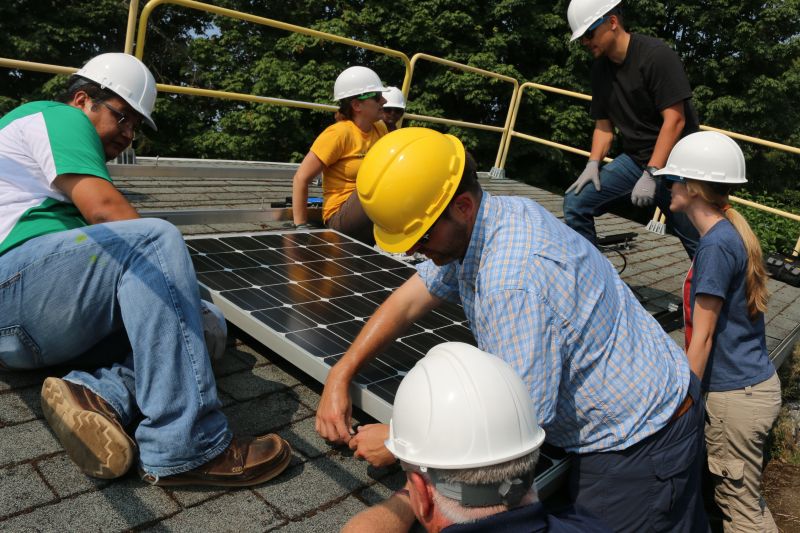 Students in hard hats working on solar panel.