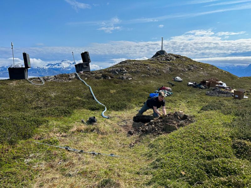 A technician installing GPS and seismic monitoring equipment on a mountainside.