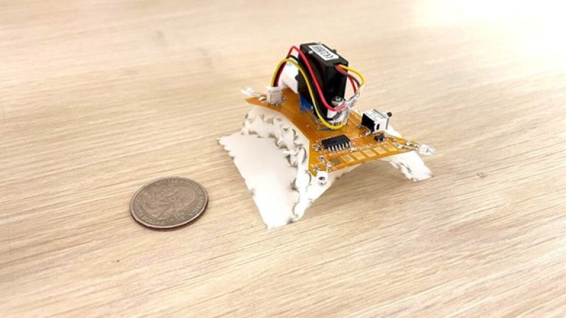 a mini robot being compared to a quarter in size