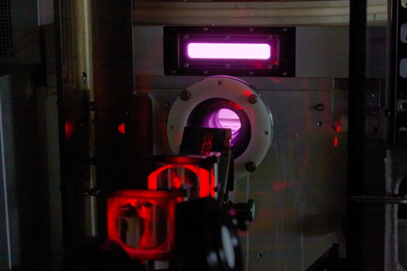 A laser table in a dark lab with red laser light visible and optical equipment.