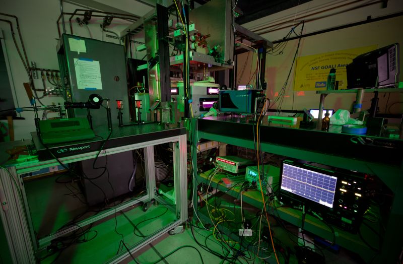 A laser table in a dark lab with red laser light visible and optical equipment.