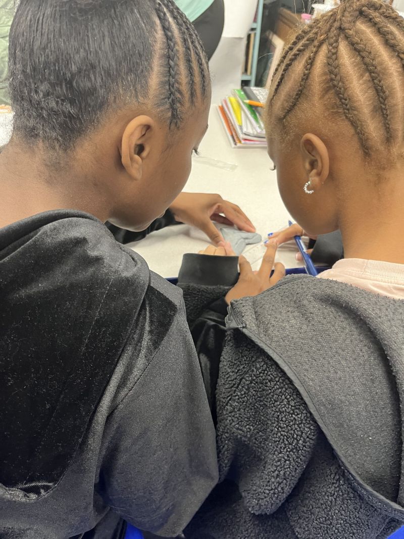 Two children at a desk, looking at shark fossils.