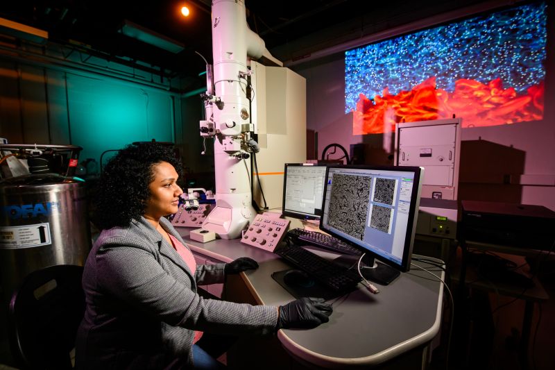 A researcher sits at a computer in a darkened lab.