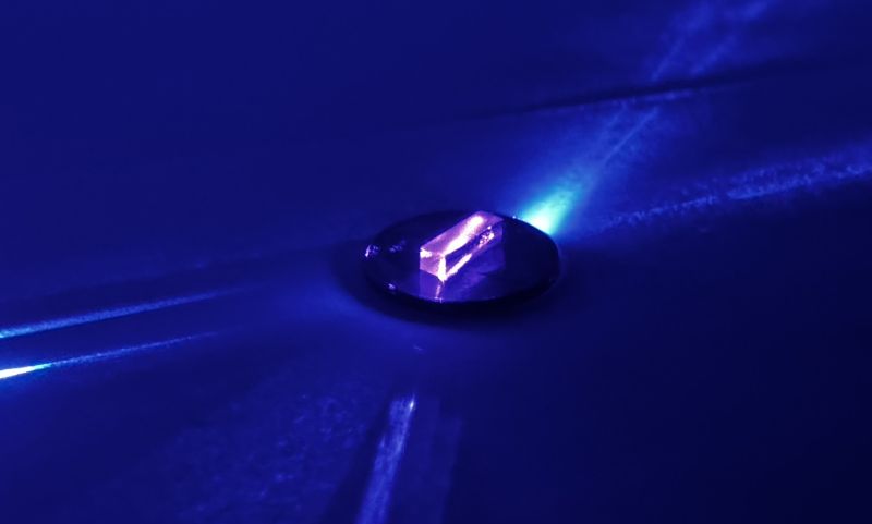 A small 3D purple rectangle illuminated with laser light.