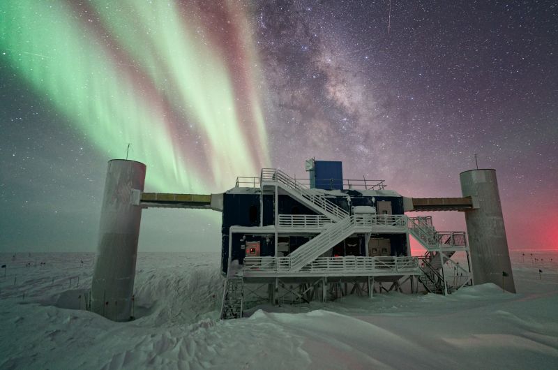 A building with steps and columns, surrounded by snow and with the Milky Way and auroras appearing in the background.
