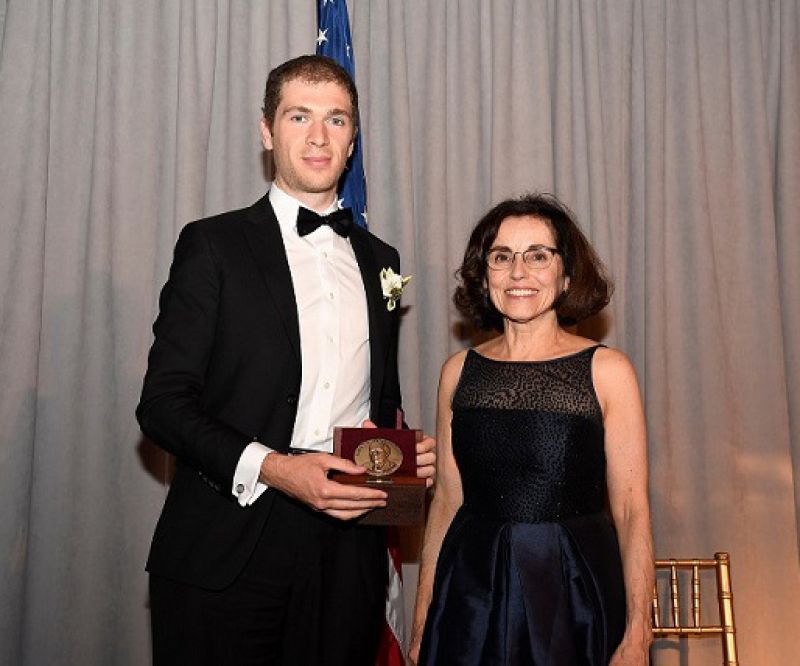 man in suit receiving award from woman