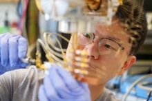 A researcher, wearing glasses, handles lab equipment.