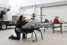 A woman working on a grey helicopter-shaped drone.