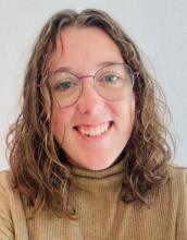 portrait of Emma Menio in tan shirt and wears glasses