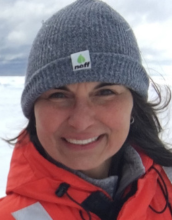 portrait of Penny Vlahos wearing a grey beanie hat and a orange jacket