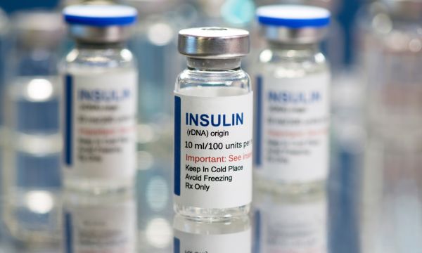 Insulin vials on meal tray with glass vials in background.