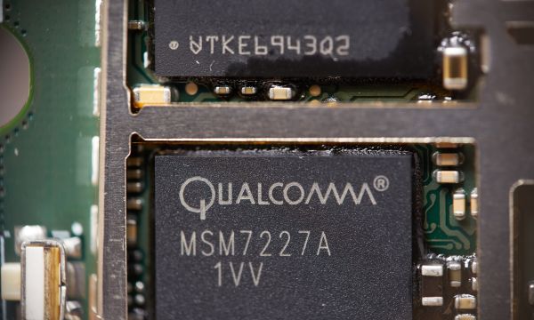 A close-up of a circuit board containing a dark box labeled 'Qualcomm.'