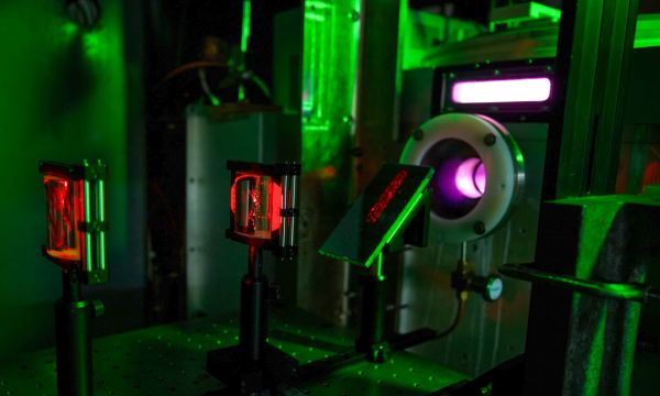 A laser table in a dark lab with red laser light visible and optical equipment.