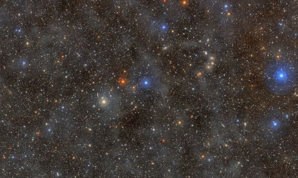 A dense field of colorful stars shining through a dust cloud