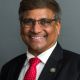 NSF's director, wearing glasses and a red tie, smiling.