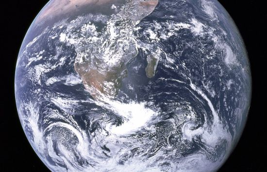 Photograph of the Earth with blue ocean and swirling white clouds set against the blackness of space