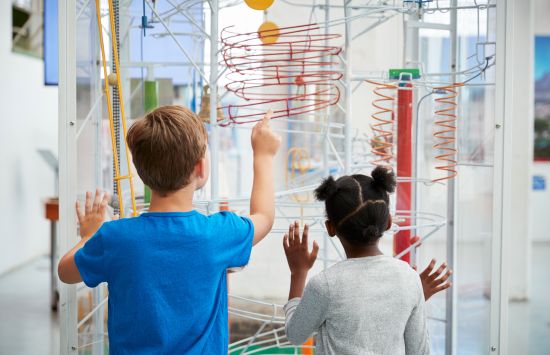 Two small children look at a colorful exhibit in a museum