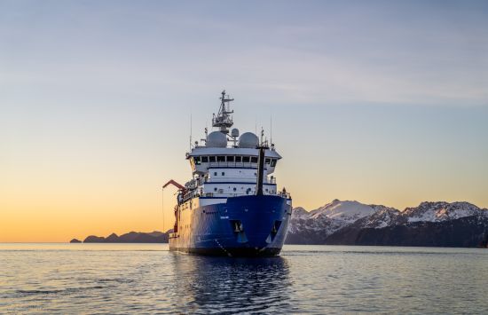 A large ship with snow covered mountains in the background
