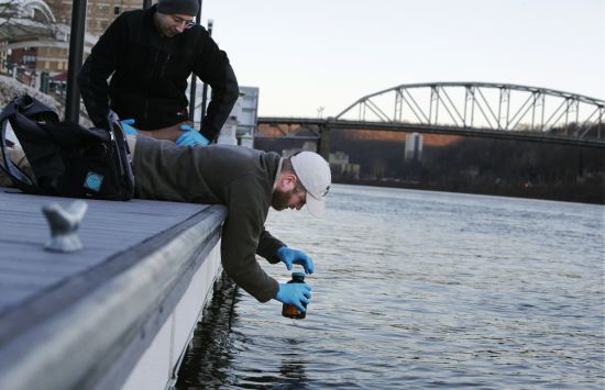 A researcher collects a water sample from a river