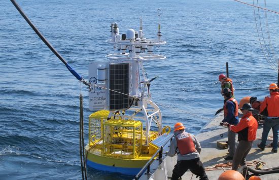 Workers on a ship releasing a scientific buoy into the ocean