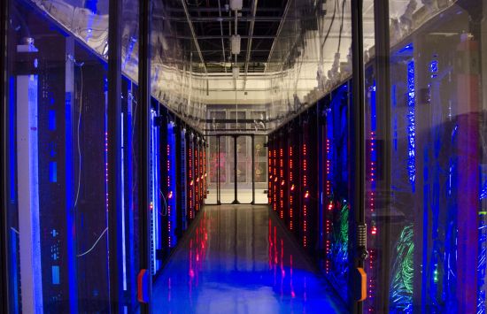 A dark hallway flanked by glowing walls of computers