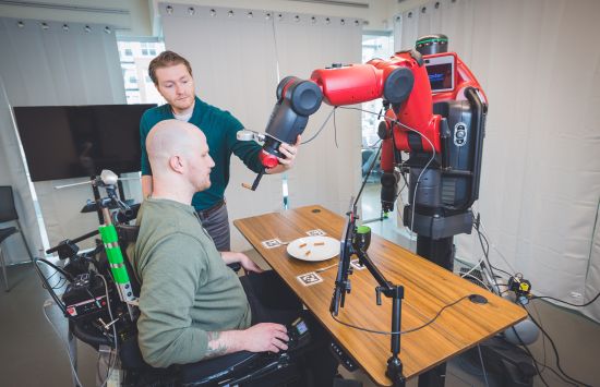 a person controls a robot to feed himself