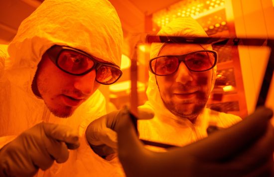 Two researchers in a lab wearing protective lab gear