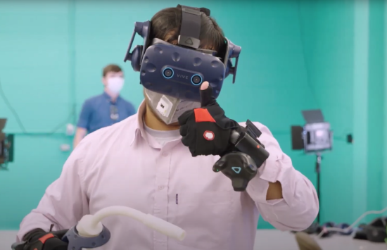 A person wearing VR goggles and giving a thumbs up