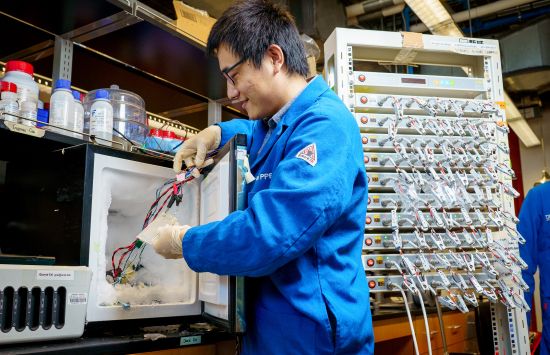 An engineer stands in front of a laboratory freezer