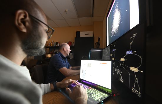 Two researchers sitting at an array of computer screens
