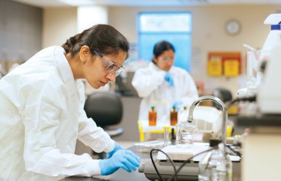 A student in a laboratory wearing a lab coat and goggles.