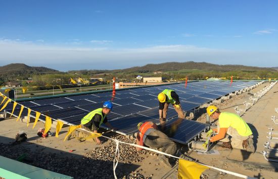 Madison College graduate Mike Reuter (in blue helmet) leads a solar panel installation crew for a renewable energy program