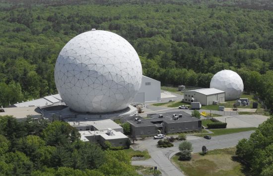 Aerial photograph of a larger and smaller white spherical building with other buildings and forests around them.