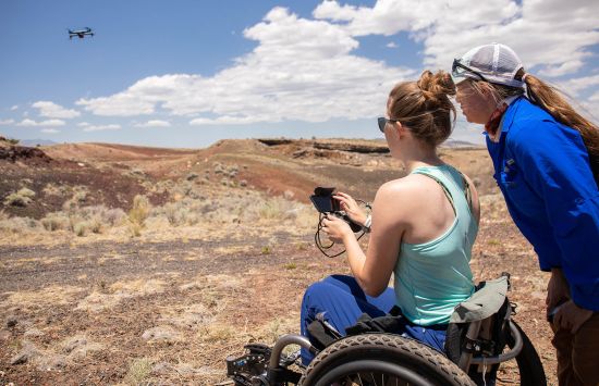 woman sitting in wheel chair controlling a flying drone