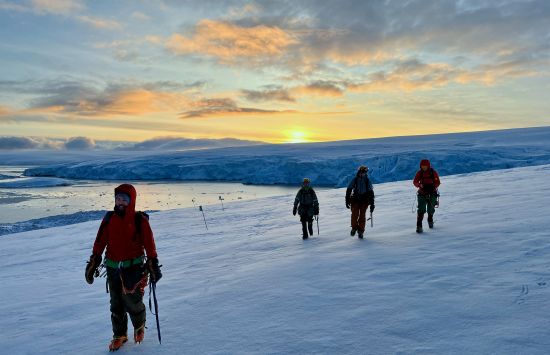 A satellite manager and members of the NSF Palmer Station Glacier Search and Rescue Team walk through the snow.