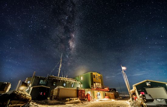 The milky way over a building in the snow.