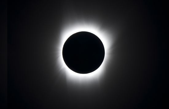 Image of a total eclipse, with the moon fully occluding the sun, surrounded by a corona of glowing light.