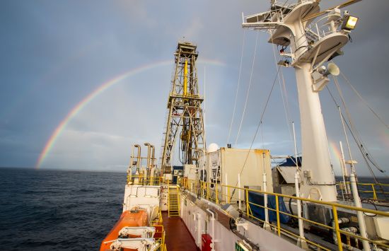Rainbow over the the deck of a research vessel covered in scaffolding and instruments.
