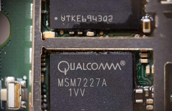 A close-up of a circuit board containing a dark box labeled 'Qualcomm.'