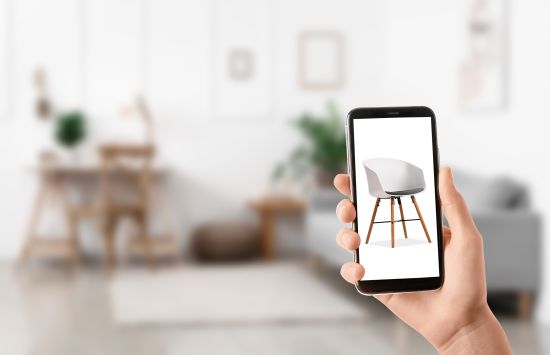 A hand holding a smartphone displaying a chair.