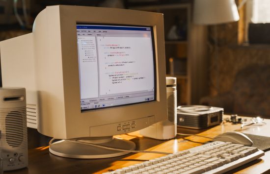 A 1990s or early 2000s era desktop computer displaying programming code on its screen.