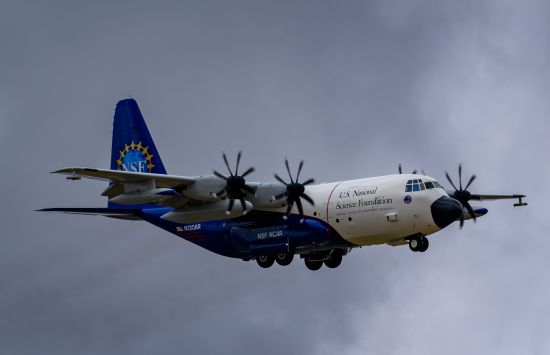 An airplane with the NSF logo on the tail and "U.S. National Science Foundation" on the side, in flight against a cloudy sky.
