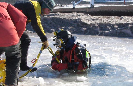 Diver Rob Robbins (left) helps diver Steve Rupp into the water to assess the underwater structure of the McMurdo pier.