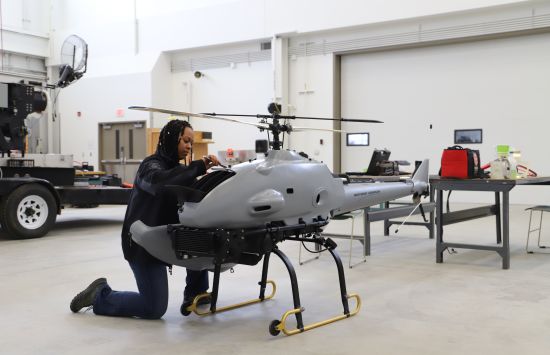 A woman working on a grey helicopter-shaped drone.