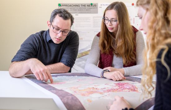 Three people studying a map on a table.